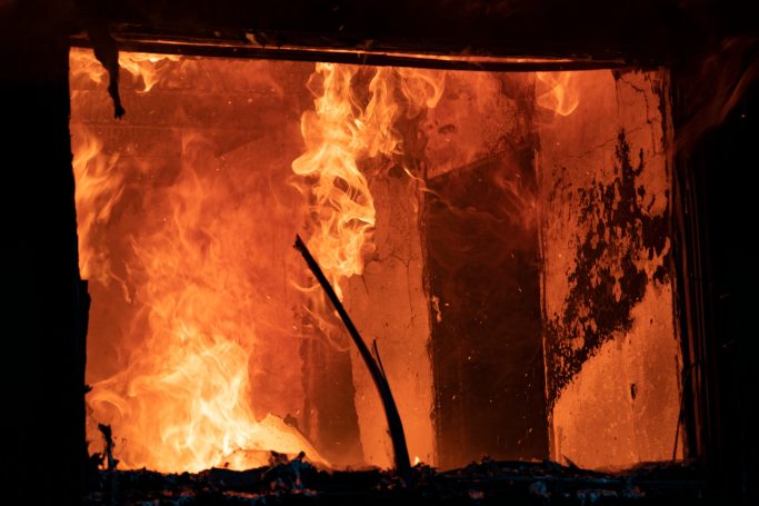 Bright flames engulfing a structure, with dark smoke rising in the background.