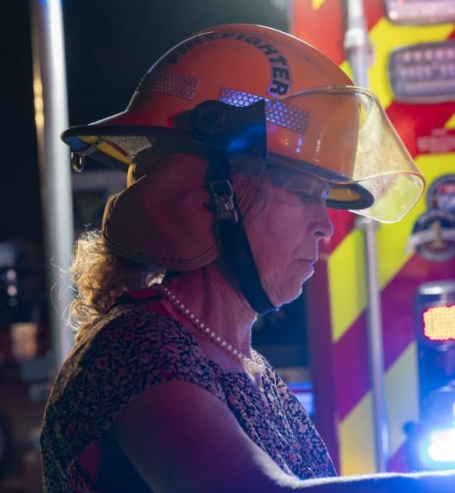 Firefighter wearing a helmet and protective gear, focused on a task at night.