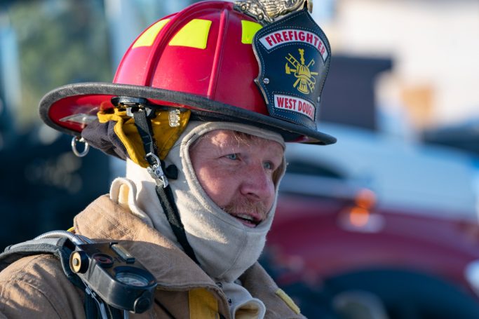 Firefighter in helmet and gear, focused and ready for action.
