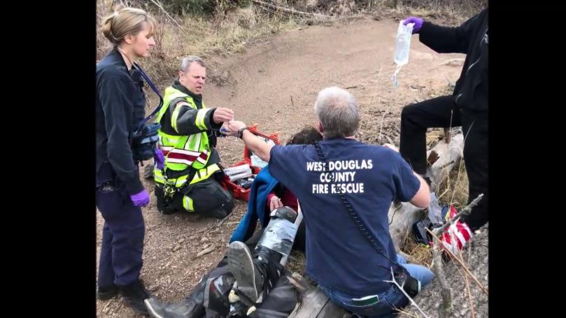 First responders assisting an injured person on a trail.