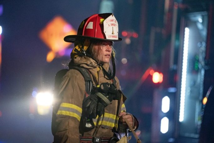 Firefighter in protective gear, helmet, and uniform, responding to an emergency scene.